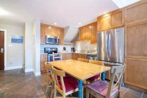 a kitchen with a wooden table and a stainless steel refrigerator at Ski-in Ski-out at upper village next to Fairmount Hotel In Whistler in Whistler