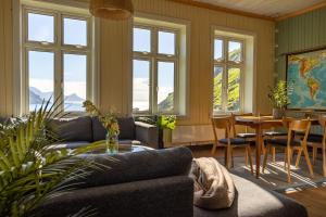 a living room with a couch and a table and windows at Feriehus med flott havutsikt ved Hauklandstranden in Leknes