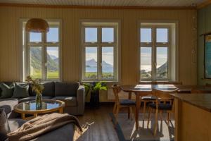 a living room with a table and chairs and windows at Feriehus med flott havutsikt ved Hauklandstranden in Leknes