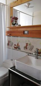 a bathroom with a sink and a toilet and a mirror at La Cabaña de Mari in Oxapampa