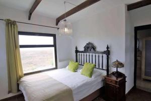a bedroom with a bed with green pillows and a window at Villa Los Palomos in San Bartolomé