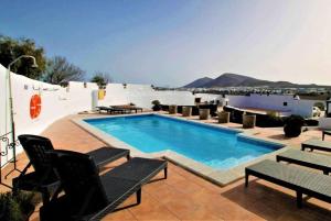 a swimming pool on a roof with chairs around it at Villa Los Palomos in San Bartolomé