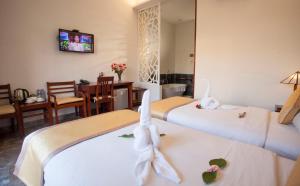 a hotel room with three beds and a dining room at Hoi An TNT Villa in Hoi An