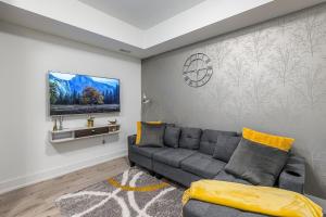 a living room with a gray couch and a tv at Exquisite 2 Bedroom Apt, mins to the falls. in Niagara Falls