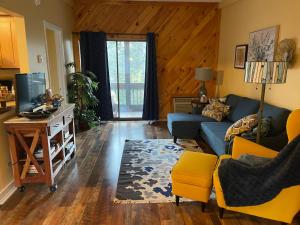 sala de estar con sofá azul y TV en Village at Winnipesaukee 59 Treetop #432, en Laconia
