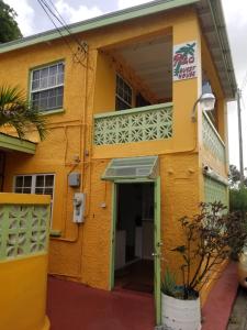 a yellow building with a door and a balcony at Rio Guesthouses in Christ Church
