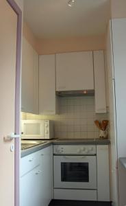 uma cozinha com armários brancos e um forno com placa de fogão em Duinroos C2 em Koksijde