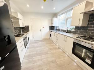 a kitchen with white cabinets and a wooden floor at Minet Gardens House - Suite 6 in London