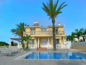 una casa con una palma e una piscina di Beach Villa Sea View, XXL Pool, 4 Bedroom a Ayia Napa