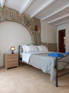 a bedroom with a bed and a stone wall at Serifos Sunset in Livadakia