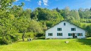 a white house on a green field with trees at Chalet Meuselotte, à Bussang dans les Vosges in Bussang
