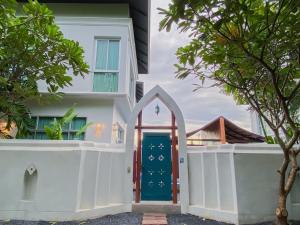 una casa blanca con una puerta azul y árboles en Twenty Two Pool Villa, en Pattaya central