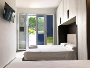 a bedroom with two beds and a sliding glass door at Quintino Apartments Pool in Torre Lapillo +15 photos