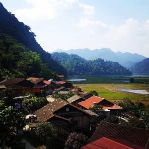 a village with a river and mountains in the background at Pac Ngoi Village Homestay in Ba Be18