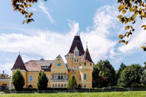 uma grande casa amarela com uma torre em Georgi Schloss - Boutique Hotel em Ehrenhausen