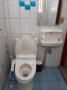 een kleine badkamer met toilet en wastafel bij Minshuku Tantawan -SEVEN Hotels and Resorts- in Motobu
