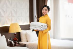 a woman holding a pile of towels in a hotel room at Hanoi Diamond King Hotel & Travel in Hanoi
