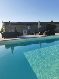 a swimming pool with blue water in front of a house at Au domaine de Gigie in Chervettes