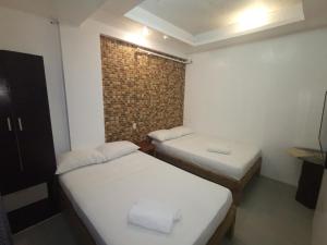 two beds in a small room with a brick wall at Taj Guesthouse Boracay in Boracay
