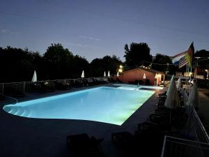 una gran piscina por la noche con sillas y sombrillas en Campeggio Tranquilla, en Baveno
