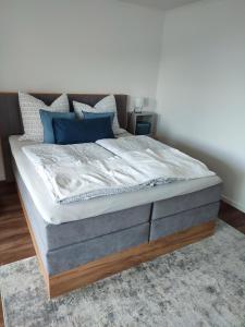 een groot bed met blauwe kussens in een slaapkamer bij Gemütliches Studio mit Ausblick, Pool und WiFi in Baiersbronn