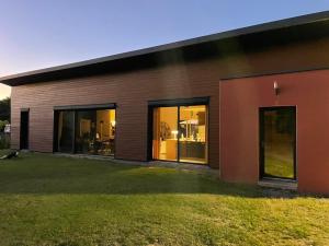 a house with large windows and a yard at Maison 150 M2 pour 6 personnes proche circuit des 24 H 