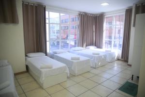 a room with two beds and a large window at Hotel Jurubatuba in São Bernardo do Campo