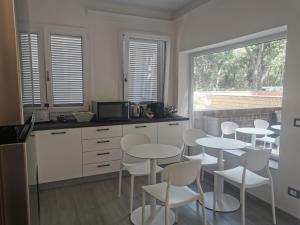 a kitchen with white tables and white chairs and a window at Puntaalarooms in Punta Ala