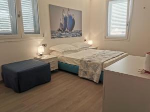 a bedroom with a bed and a table and two windows at Puntaalarooms in Punta Ala