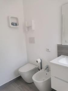a white bathroom with a toilet and a sink at Puntaalarooms in Punta Ala