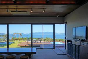 a living room with a view of a playground and a table at Seaside Villa SASAO in Aji