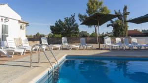 a group of chairs and umbrellas next to a swimming pool at Villa Las Tres Hermanas Albarreal de Tajo by Toledo AP in Albarreal de Tajo