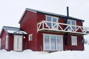 a red house with a balcony on top of it at Nesseby Guesthouse in Varangerbotn