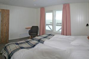 1 dormitorio con 1 cama, 1 silla y 1 ventana en Nesseby Guesthouse en Varangerbotn