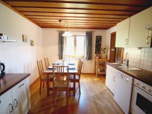 een keuken met een tafel en stoelen en een keuken met witte kasten bij Appartement Herzogbauer in Saalfelden am Steinernen Meer