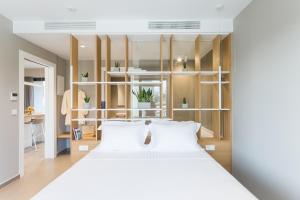una camera da letto con un grande letto bianco con cuscini bianchi di Noemie Luxury Suites a Chania