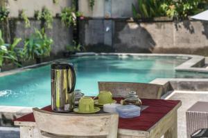 a table with a blender on it next to a swimming pool at Adi Santia Bungalows in Ubud