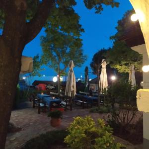 a patio with tables and umbrellas at night at Gastland M1 Hotel & Conference Center in Páty +49 photos