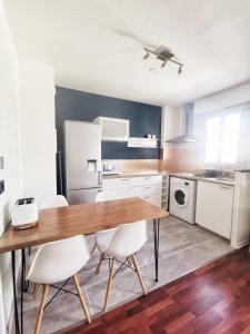 a kitchen with a wooden table and white chairs at Le 100 Brossolette in Noisy-le-Grand +11 photos