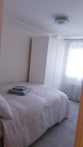 a bedroom with a white bed and a window at Lovely 2 bedroom flat in the heart of water Wimbledon in London