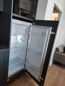 um frigorífico vazio com a porta aberta e um micro-ondas em LE REFLET DES VOILES FACE AU PORT DE FECAMP em Fécamp