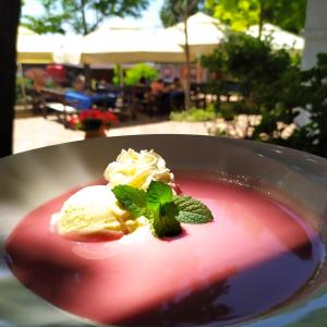 a bowl of dessert with ice cream and a mint leaf at Gastland M1 Hotel & Conference Center in Páty