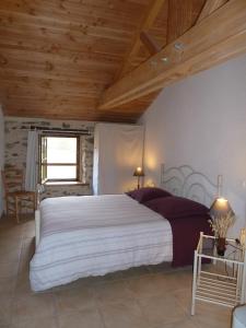 um quarto com uma cama grande e um tecto de madeira em Le Moulin de Drapras em Chemillé