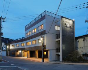 Tabist Onsen Petit Hotel Yukori Bandai Atami في كورياما: مبنى طويل مع علامة على الجانب منه