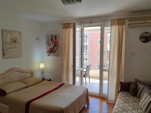 a bedroom with a bed and a sliding glass door at Apartman Avanti in Budva
