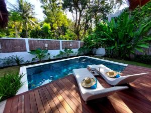 a backyard with a swimming pool and a wooden deck at Villa Saia in Gili Islands
