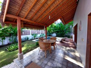 a patio with a table and chairs under a wooden pergola at Villa Saia in Gili Air