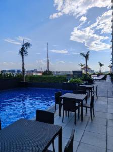 un patio con tavoli e sedie accanto alla piscina di Schönes Apartment mit Pool-Nutzung a Manila