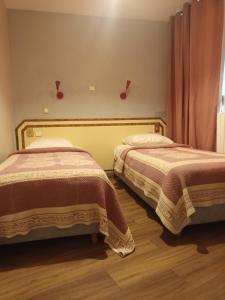 two beds in a room with two bedsskirtspectspectssenalsenalsenalsenalsenal at Hôtel de Lorraine in Paris
