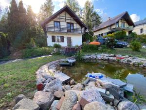 a backyard with a pond in front of a house at Kaszuby Dom Letniskowy -u Remika- Holiday Home Sulęczyno in Å»akowo